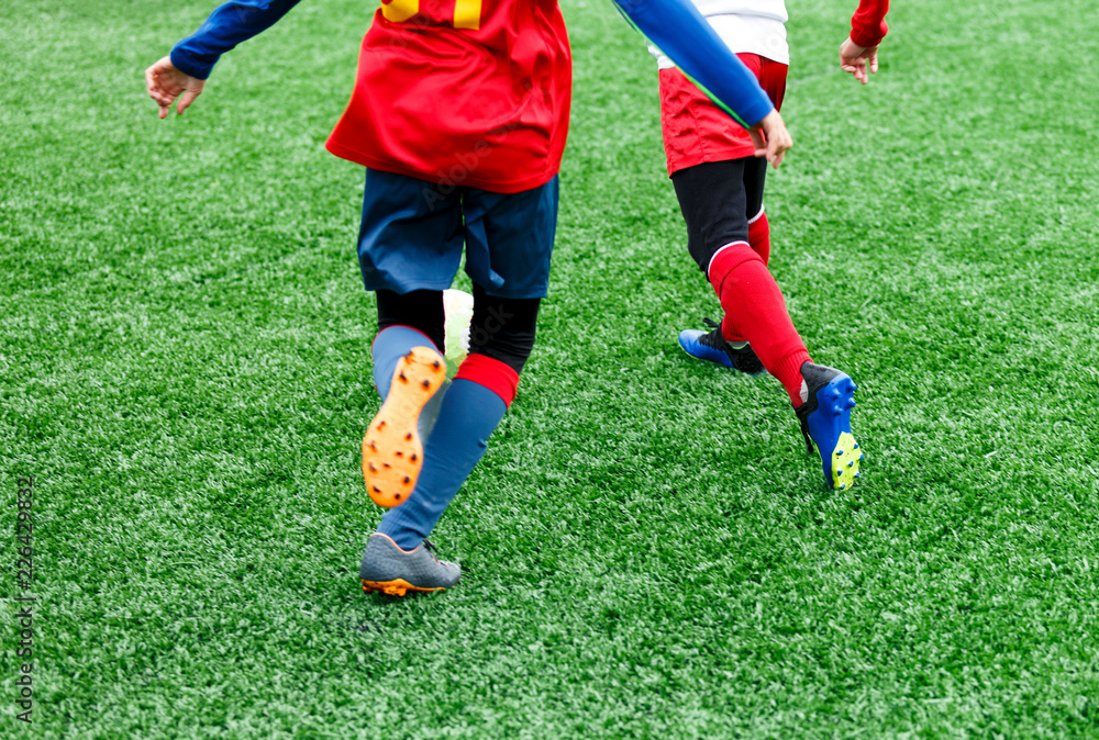 football teams - boys in red, blue, white uniform play soccer on the green field. boys dribbling. dribbling skills. Team game, training, active lifestyle, hobby, sport for kids concept football teams - boys in red, blue, white uniform play soccer on the green field. boys dribbling. dribbling skills. Team game, training, active lifestyle, hobby, sport for kids concept
