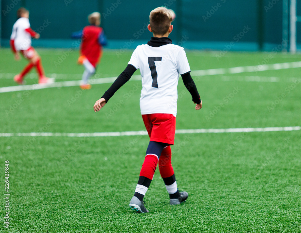 football teams - boys in red, blue, white uniform play soccer on the green field. boys dribbling. dribbling skills. Team game, training, active lifestyle, hobby, sport for kids concept	