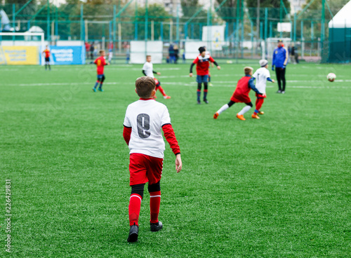 football teams - boys in red  blue  white uniform play soccer on the green field. boys dribbling. dribbling skills. Team game  training  active lifestyle  hobby  sport for kids concept 