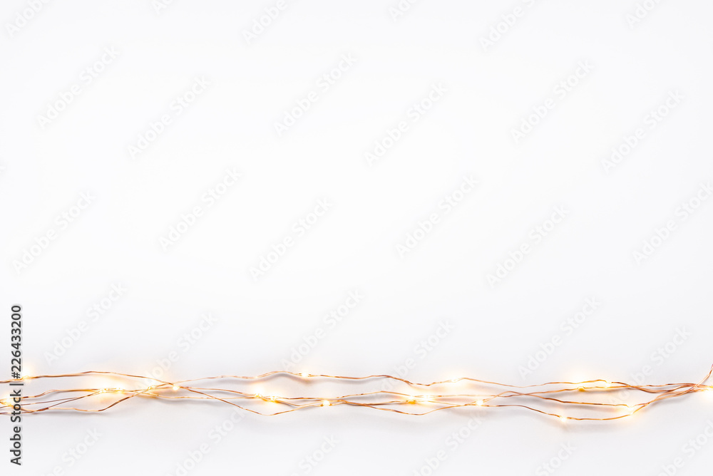 Christmas lights garland border over white background. Flat lay, copy space.