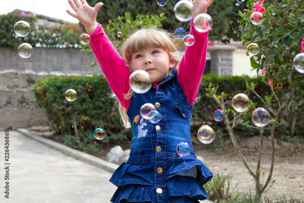 Little girl playing with soap bubbles in the garden Little girl playing with soap bubbles in the garden