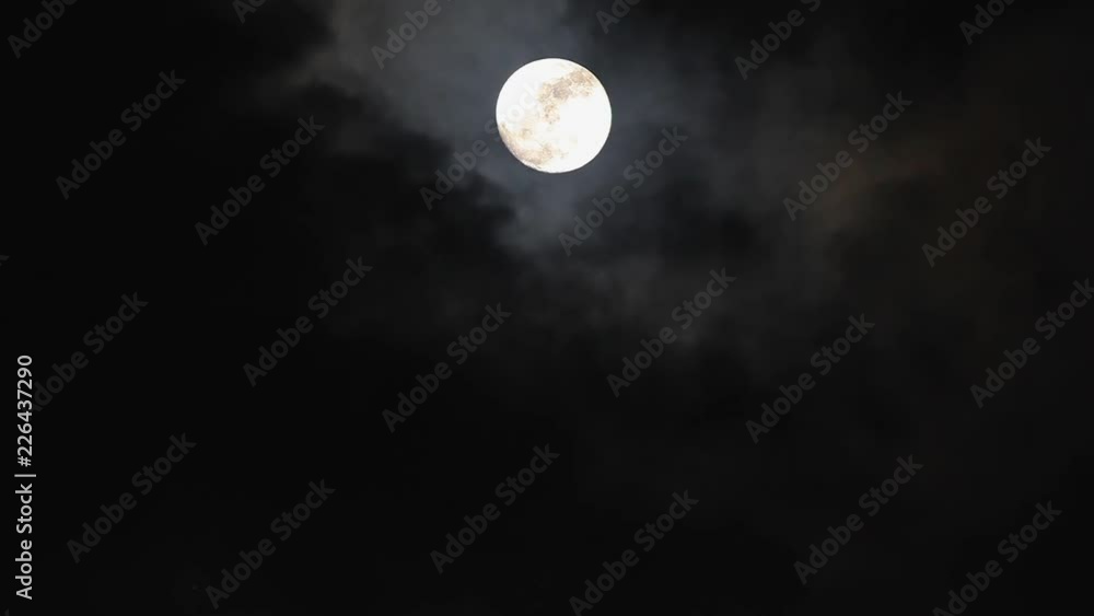 Black clouds passing in front of the moon in the night sky. Outdoor at nighttime.. Black clouds passing in front of the moon in the night sky. Outdoor at nighttime..