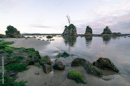 Pacific ocean coast at evening, overlooking Tillamook Bay, Oregon. Rock formations stick out of the still water. photo