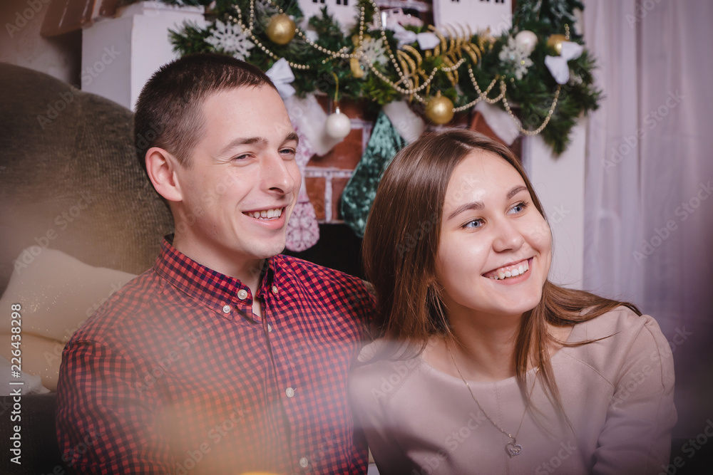 Young couple celebrating in the room decorated for Mary Christmas and New year Young couple celebrating in the room decorated for Mary Christmas and New year