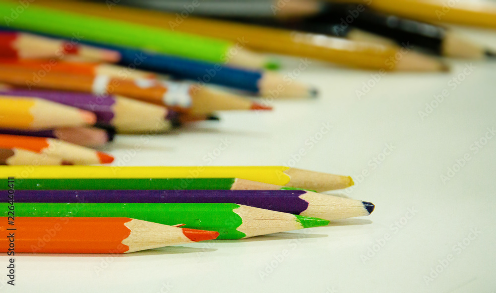 In selective focus of used color pencil on table,blurry light design background