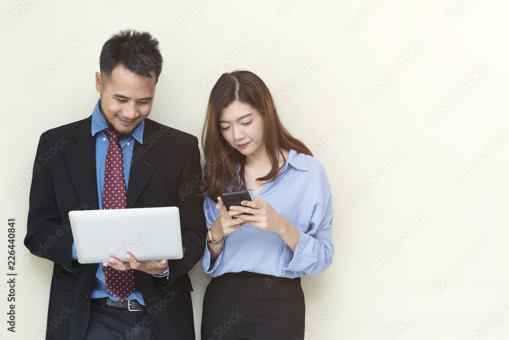 Business people standing on wall and working with mobile and laptop with smiling. Success business and technology concept with free space. Picture for add text message. Backdrop for design art work. Business people standing on wall and working with mobile and laptop with smiling. Success business and technology concept with free space. Picture for add text message. Backdrop for design art work.