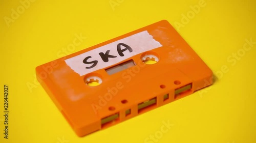 Writing the text Ska on the rough label of a vintage cassette tape (obsolete music technology). Colorful scene.
