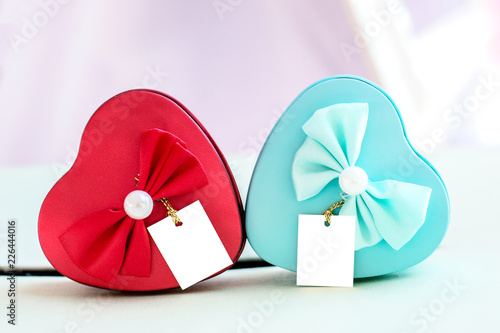 Blue and red heart box decorated with bow and pearls placed on the table.