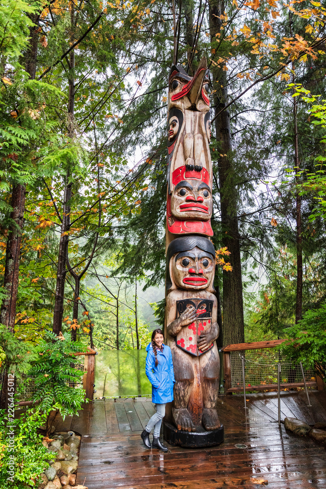 Fototapeta premium Turysta Vancouver pozuje przez słup totemu, Kolumbia Brytyjska, Kanada. Azjatycka dziewczyna odwiedza słynną atrakcję turystyczną jesienią.