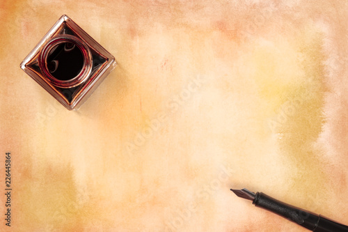 An overhead photo of an ink well with brown craft paper and an ink pen, shot from above with copy space photo