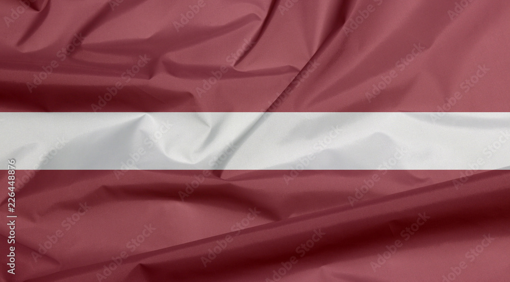 Fabric flag of Latvia. Crease of Latvian flag background, a carmine field bisected by a narrow white stripe.