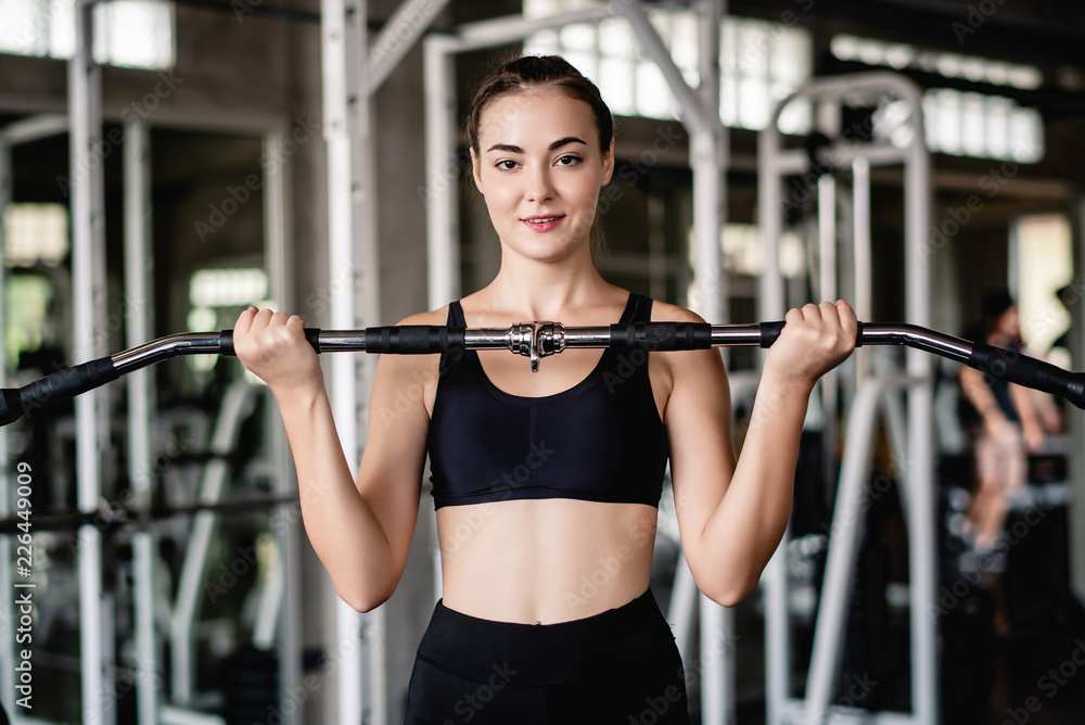 Cinematic tone of young attractive fitness woman exercise with machine in gym. Individual sport to fit muscles of body for healthy life concept. 