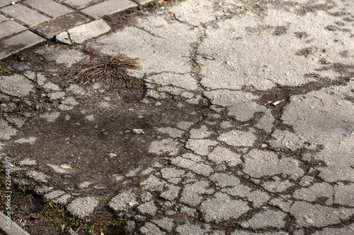 Damaged asphalt road with potholes, caused by freeze-thaw cycles in winter. Bad road. Broken pavements sidewalks on sidewalk. pavement with paving slabs with defects and cracks coming in perspective