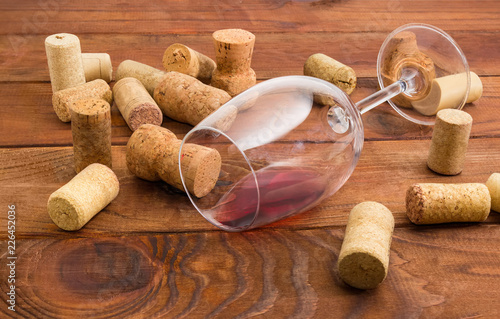 Glass with wine lying on its side among of corks