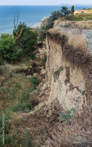 Mountain landslide disaster in sesmically dangerous area. Large cracks in earth, descent of large layers of earth blocking road. Mortal danger of damming people at foot of landslide slopes of mountain