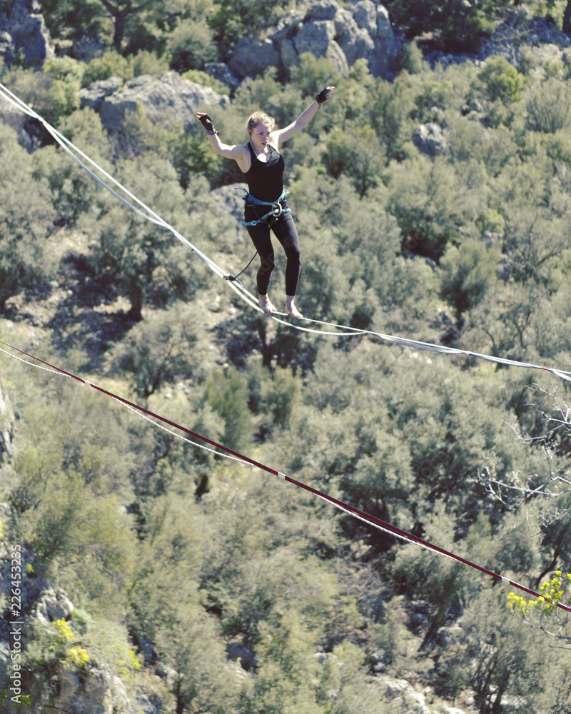 Obraz premium Highliner on a rope. Highline on a background of mountains. Extreme sport on the nature. Balancing on the sling. Equilibrium at altitude.