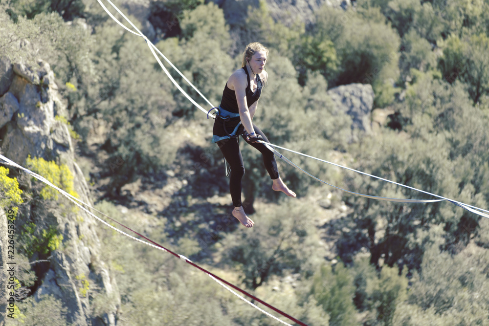 Obraz premium Highliner on a rope. Highline on a background of mountains. Extreme sport on the nature. Balancing on the sling. Equilibrium at altitude.