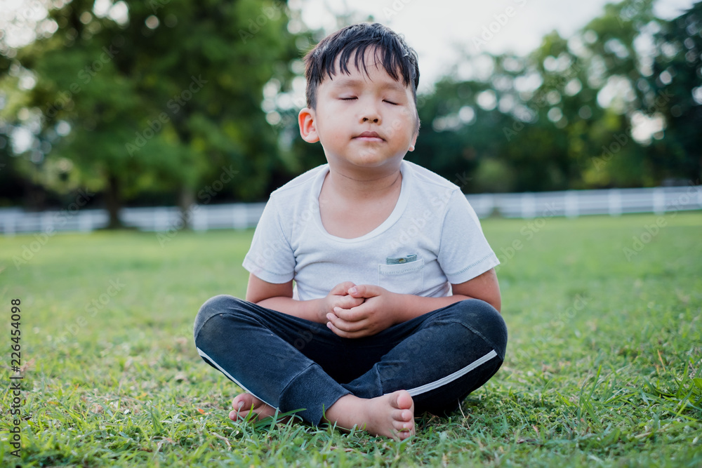 Asian little boy meditation with peace and relax in the park outdoor.Meditation concept with copy space. Asian little boy meditation with peace and relax in the park outdoor.Meditation concept with copy space.