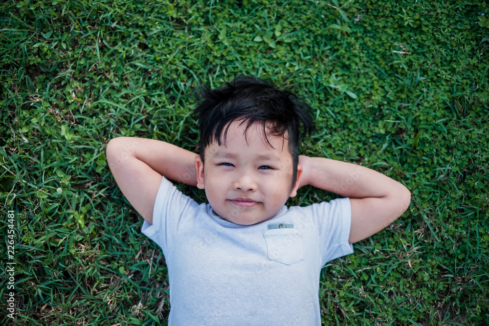 Little Asian child laying down on the grass.Top view Little Asian child laying down on the grass.Top view
