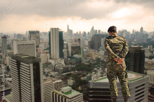 Back view. Soldier in camouflage uniforms, hands behind his backs on urban city background,democracy security concept. photo