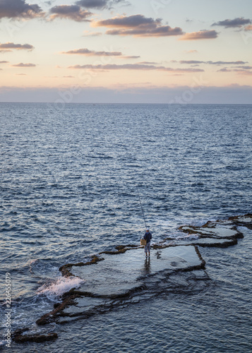 Fisherman fishing in sea during sunset