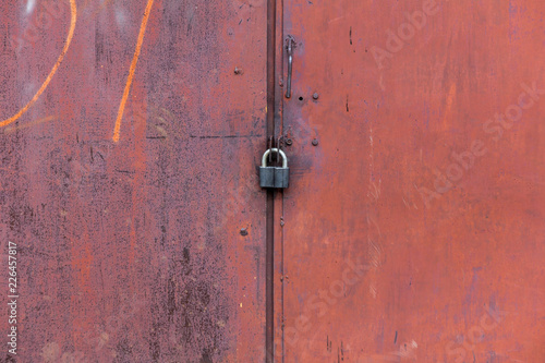 rusty metal door closed on the padlock. old metal texture
