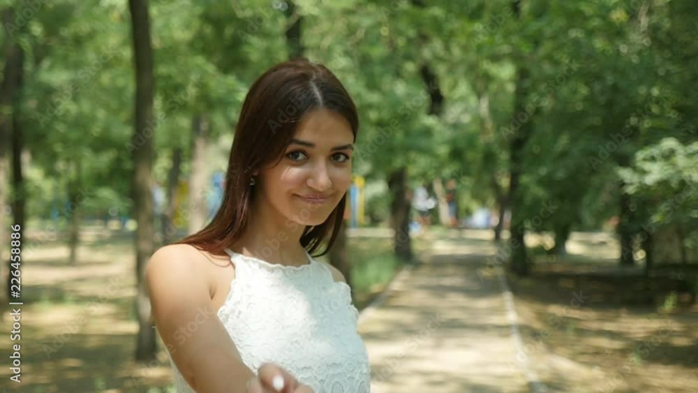 Cheery view of a romantic young woman with long loose hair smiling and dancing enigmatically in a foliar forest on a sunny day in summer Cheery view of a romantic young woman with long loose hair smiling and dancing enigmatically in a foliar forest on a sunny day in summer