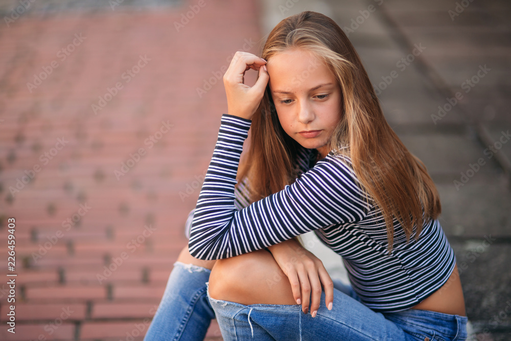 young teenage poses for photo. blonde girl in jeans and blouse