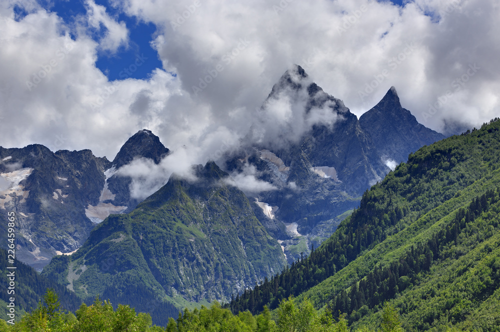 Obraz premium Peak of the mountain with glaciers against the background of clouds and sky. Caucasian ridge, Russia.