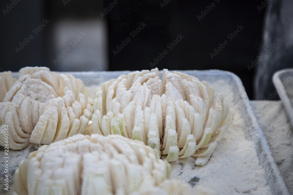 Isolated close up view of floured blooming onions on metal tray with out of focus backgrounds Isolated close up view of floured blooming onions on metal tray with out of focus backgrounds