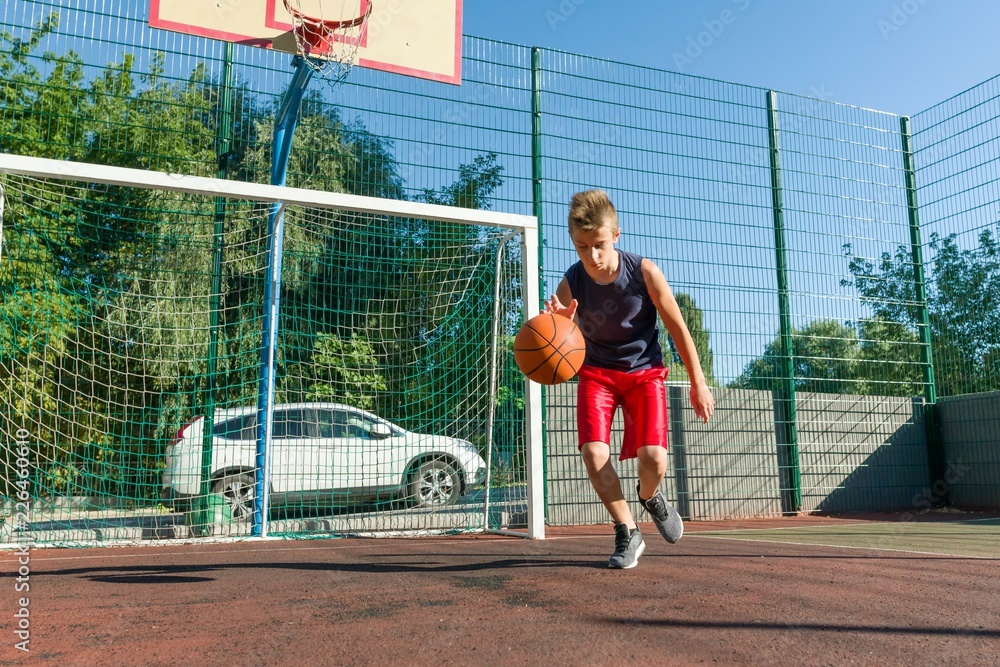 Outdoor portrait street basketball player playing with the ball on sunny day Outdoor portrait street basketball player playing with the ball on sunny day