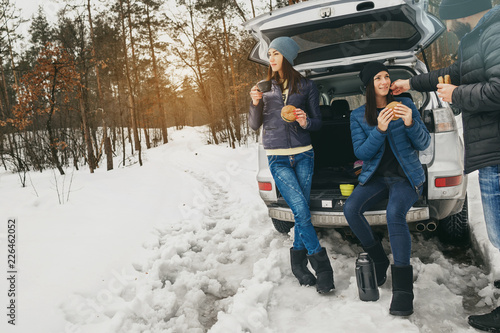 Group friends winter wear snowy winter forest talk drinking coffee car