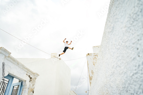 Mann macht Parkour und springt über die weißen Hausdächer in Santorin 