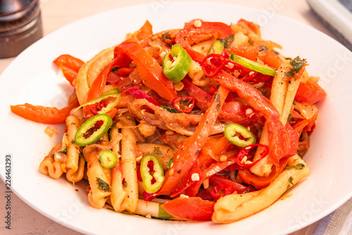 Italian food - Pasta with peppers and onions on a white plate close-up
