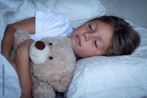 Photography Portrait of a young girl (kid) sleeping in the bed with the teddy bear