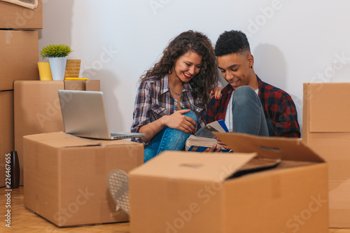 Happy young couple moving into their new home. They sitting on the floor and choosing colors for the walls.