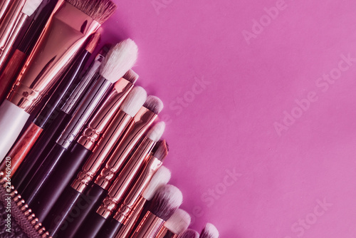 many makeup brushes on pink bright background