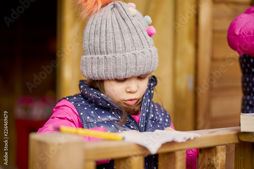 Photography pretty little girl in a hat and jacket is playing on a treehouse in an autumn fo