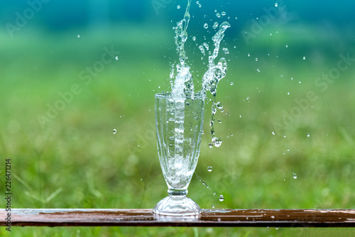 Drink water pouring in to glass over sunlight and natural green background.Select focus blurred background.Fresh Clean water splash. © noon@photo