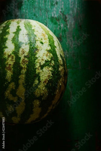 A large ripe watermelon on a dark green background.