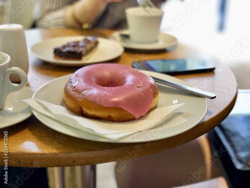 Pink icing glazed donut in a cafe