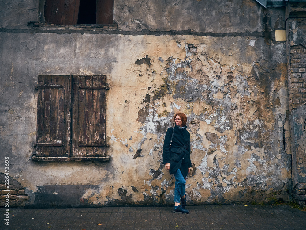 Red-haired young girl near an old house.