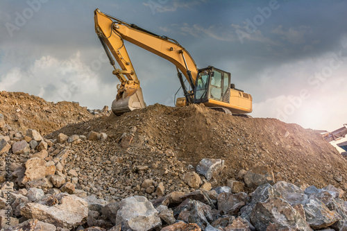 A large yellow excavator moving stone in a quarry photo