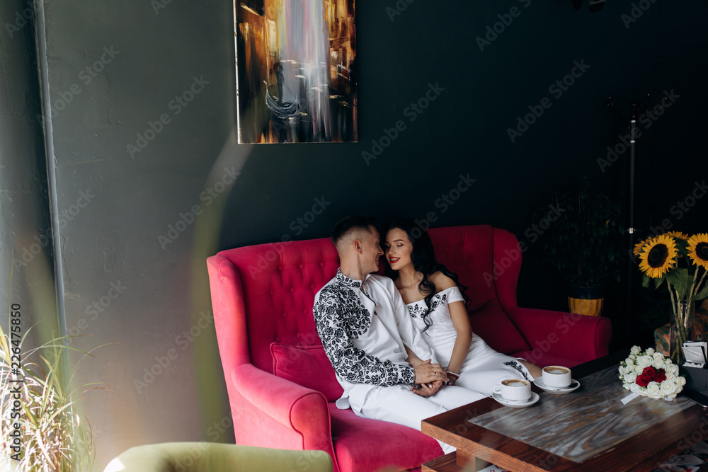 Obraz premium Cheerful newlyweds rest on a bright pink sofa in the cafe