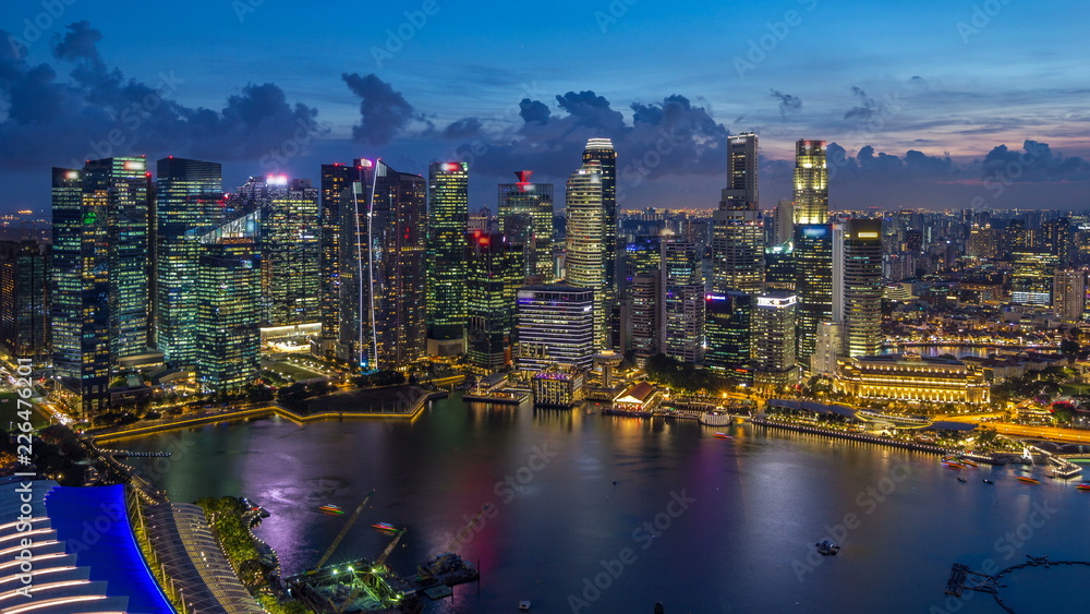 A view of Singapore business district skyscrapers at evening with water reflections day to night