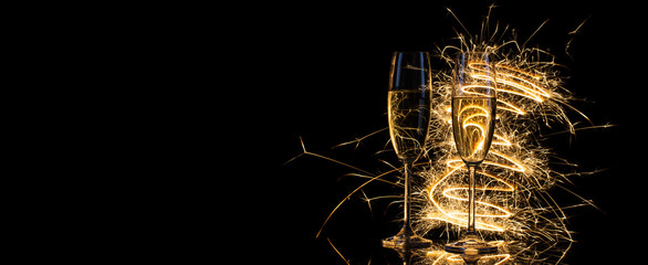Glasses with champagne in the golden light of Bengal lights