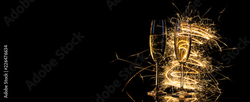 Glasses with champagne in the golden light of Bengal lights