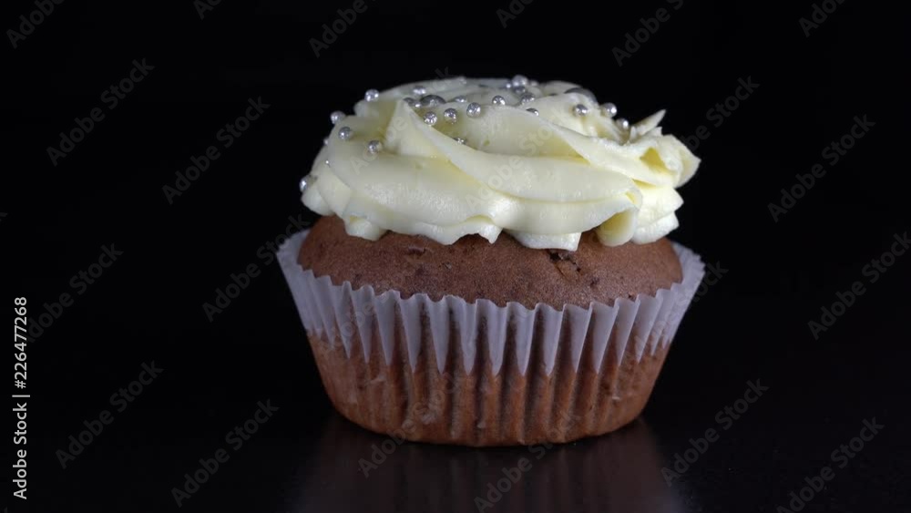 Fragrant, vanilla cupcake with berry filling and honey cream cheese on black background, close up, rotates Fragrant, vanilla cupcake with berry filling and honey cream cheese on black background, close up, rotates