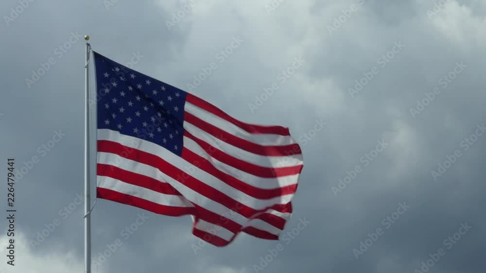 US flag flying with cloudy sky in the background. Stars and Stripes of the United States of America, symbol and concept of American freedom, liberty, democracy. Copy space US flag flying with cloudy sky in the background. Stars and Stripes of the United States of America, symbol and concept of American freedom, liberty, democracy. Copy space
