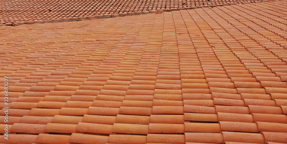 Detail of construction with red roof tiles. Roof tiles are designed mainly to keep out rain, and are traditionally made from locally available materials such as terracotta or slate. Detail of construction with red roof tiles. Roof tiles are designed mainly to keep out rain, and are traditionally made from locally available materials such as terracotta or slate.
